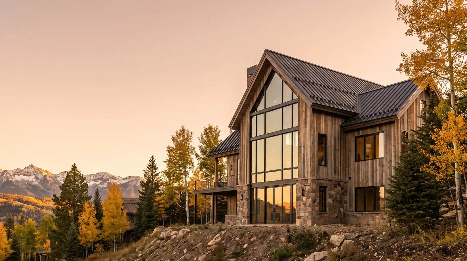 A timber and black-framed glass mountain home among golden aspens at sunset